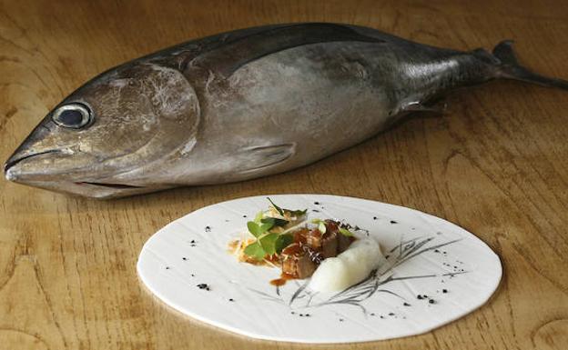 Un bonito y, junto a él, un plato con ensalada de papaya y ventresca de bonito, del Restaurante Regueiro, de Tox (Navia)
