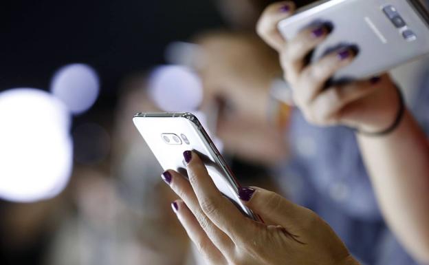 Dos jóvenes, con su teléfono móvil. /Efe