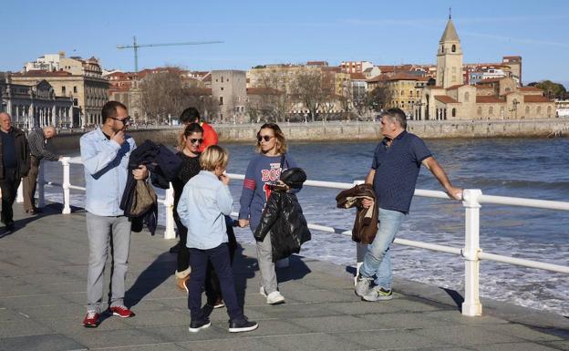 Varias personas pasean por el entorno de la playa de San Lorenzo de Gijón./Damián Arienza