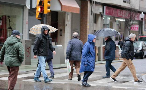Varias personas pasean bajo la lluvia por Gijón./Aurelio Flórez