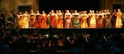 Mariano Rivas, en primer término, dirige la orquesta frente a un escenario colorista y repleto de intérpretesdurante la representación . /JOAQUÍN BILBAO/