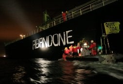 Activistas de Greenpeace pintan en el barco la frase 'Abandonemos el carbón'. / AFP/