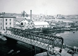 Antiguo puente metálico de San Sebastián, con las instalaciones de la factoría al fondo. / ARCHIVO NARDO VILLABOY/