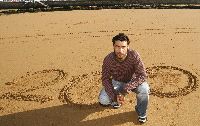BICENTENARIO. Sastre, sobre la arena de San Lorenzo, con un dibujo del número de partidos oficiales que lleva como futbolista rojiblanco. / JOAQUÍN BILBAO/