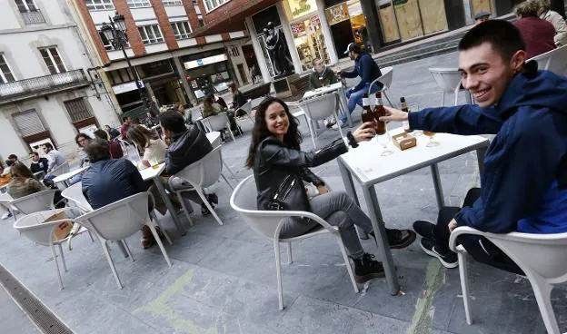 Dos jóvenes, brindando en la terraza de Casa Conrado, que ocupó con una docena de mesas la plaza de Juan XXIII desde las doce del mediodía. / FOTOS: PABLO LORENZANA