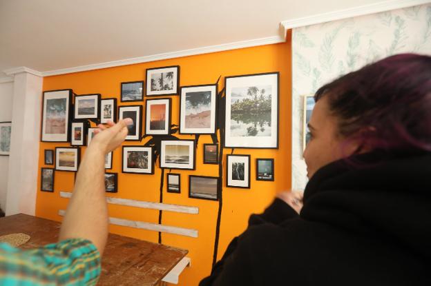 Dos visitantes comentan la exposición fotográfica de Tony Prat en la Escuela de Surf Las Dunas. / OMAR ANTUÑA